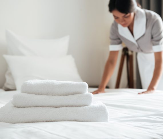 Young hotel maid making the bed with clean fresh towels